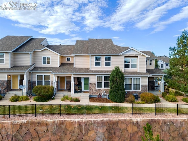 7375 Sandy Springs Pt, Fountain, CO 80817 - view of front of property with a fenced front yard, stone siding, and roof with shingles