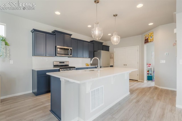 kitchen featuring light wood-type flooring, sink, appliances with stainless steel finishes, and a kitchen island with sink