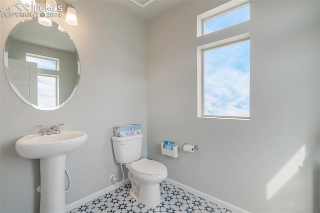 bathroom featuring toilet, plenty of natural light, and sink