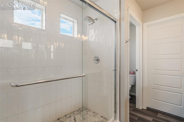 bathroom with a shower with shower door, toilet, and hardwood / wood-style floors