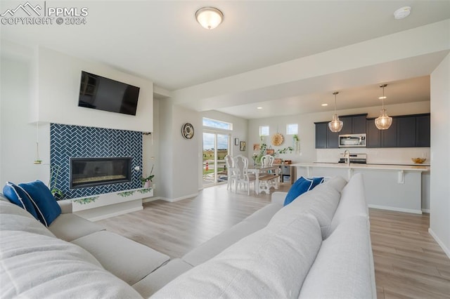 living room featuring a tiled fireplace and light hardwood / wood-style flooring