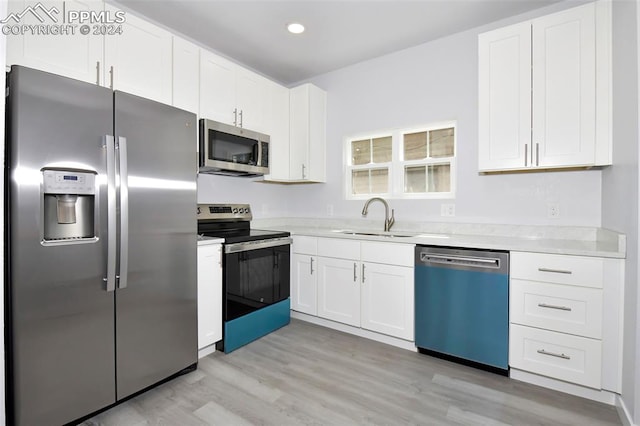 kitchen featuring appliances with stainless steel finishes, sink, white cabinets, and light hardwood / wood-style floors