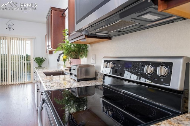 kitchen featuring stainless steel electric stove, light stone counters, dark hardwood / wood-style flooring, and sink