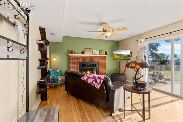 living room featuring a fireplace, light hardwood / wood-style flooring, and ceiling fan