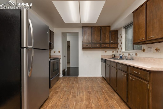 kitchen with sink, dark brown cabinetry, appliances with stainless steel finishes, and light hardwood / wood-style floors