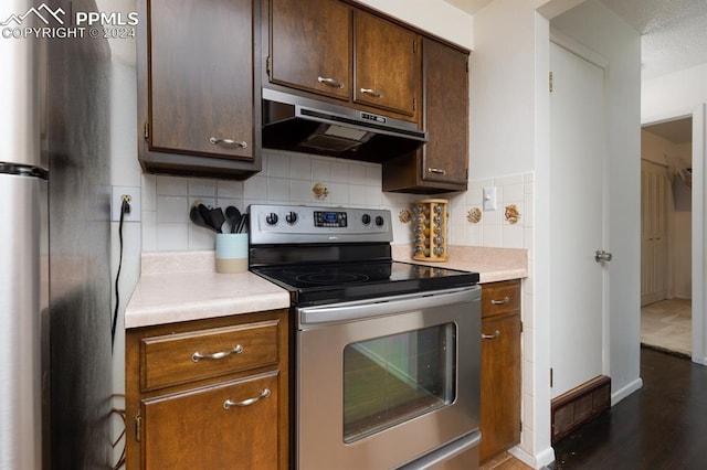 kitchen with dark wood-type flooring, tasteful backsplash, and stainless steel range with electric cooktop