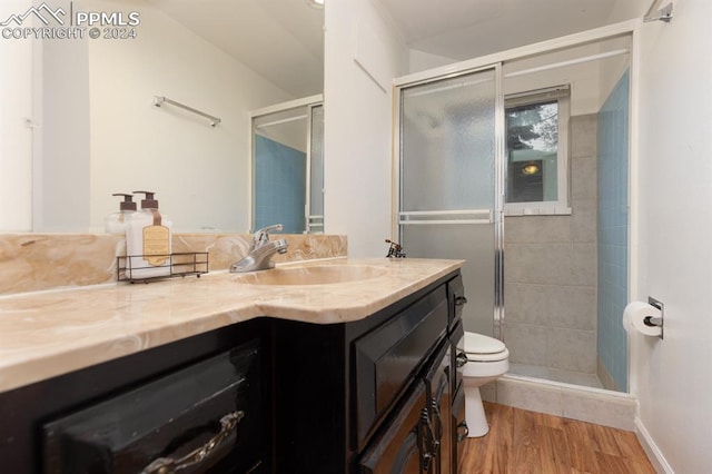 bathroom with vanity, toilet, an enclosed shower, and wood-type flooring