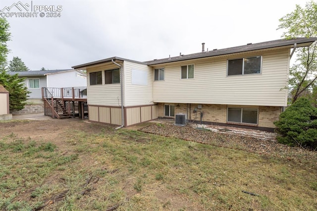 back of house with central air condition unit, a wooden deck, and a yard