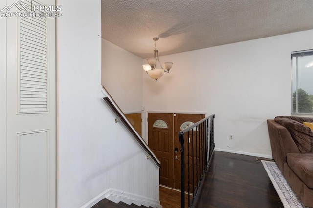 foyer entrance featuring dark hardwood / wood-style flooring, a notable chandelier, and a textured ceiling