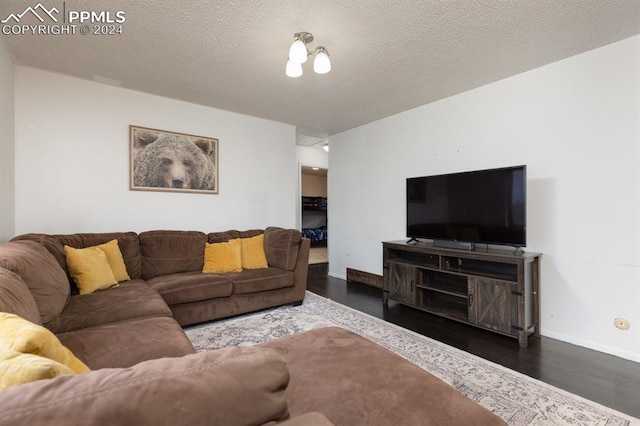 living room featuring dark wood-type flooring and a textured ceiling