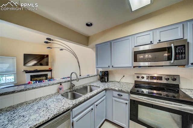 kitchen with stainless steel appliances, sink, backsplash, and kitchen peninsula