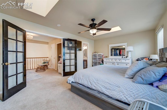 carpeted bedroom featuring ensuite bath, a skylight, and ceiling fan