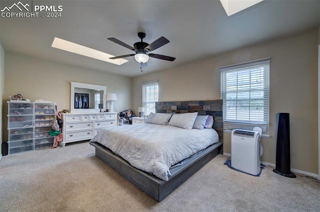 bedroom featuring light carpet, a skylight, and ceiling fan