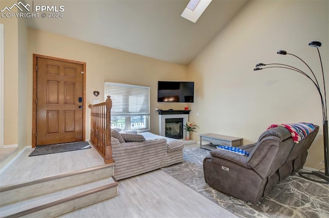 living room featuring high vaulted ceiling, a skylight, and wood-type flooring