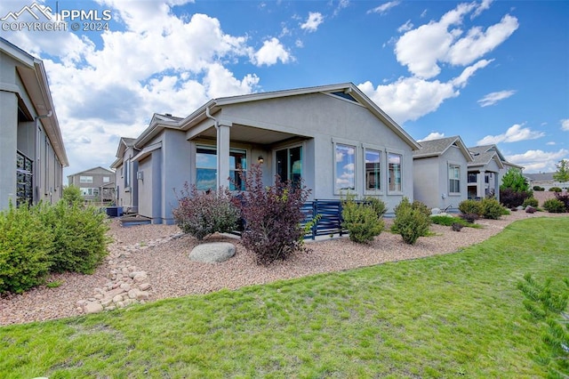 rear view of property with a lawn and central air condition unit