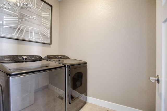 clothes washing area with washing machine and dryer and light tile patterned floors