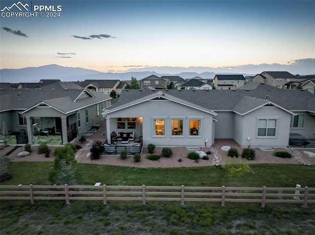 back house at dusk with outdoor lounge area, a yard, a patio, and a mountain view