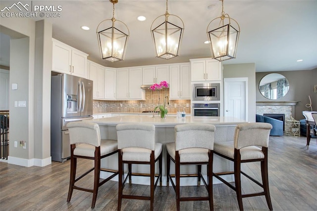 kitchen with dark wood-type flooring, pendant lighting, appliances with stainless steel finishes, and white cabinetry