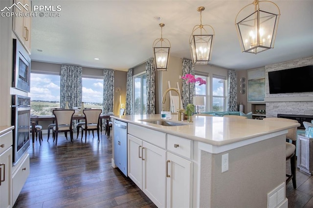 kitchen with pendant lighting, stainless steel appliances, an island with sink, and sink