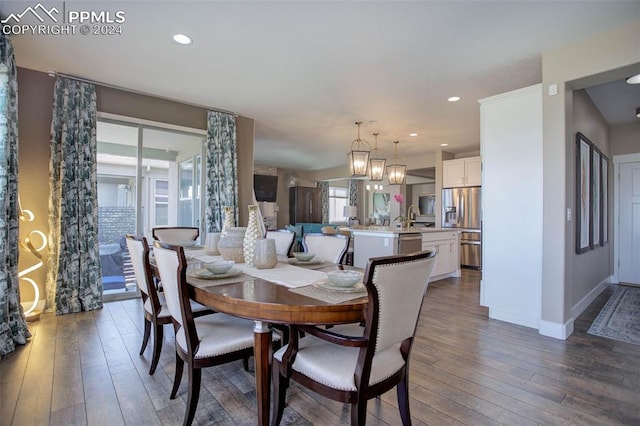 dining area featuring an inviting chandelier, sink, and dark hardwood / wood-style flooring