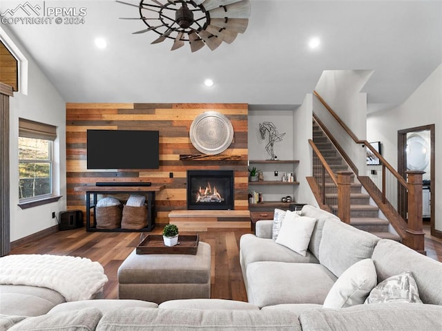 living room with lofted ceiling, hardwood / wood-style floors, ceiling fan, and wooden walls