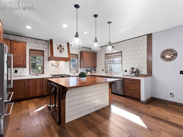 kitchen featuring stainless steel appliances, dark hardwood / wood-style flooring, wooden counters, a breakfast bar area, and a kitchen island