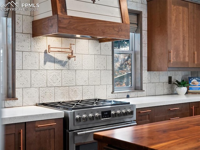 kitchen featuring high end stainless steel range, custom range hood, and tasteful backsplash