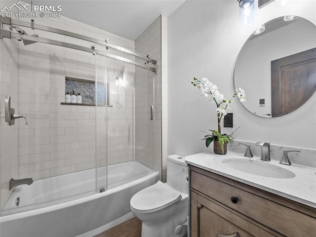 full bathroom with enclosed tub / shower combo, toilet, and vanity