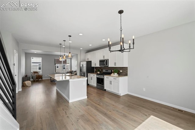 kitchen featuring an island with sink, white cabinetry, stainless steel appliances, and pendant lighting