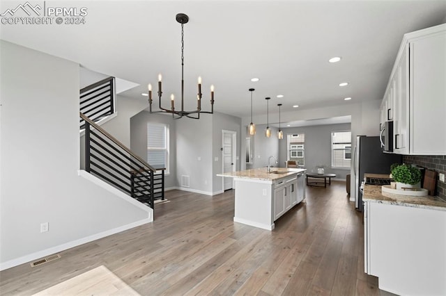 kitchen with white cabinets, a kitchen island with sink, hardwood / wood-style flooring, pendant lighting, and sink