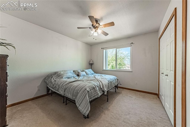 bedroom featuring light carpet, ceiling fan, and a closet