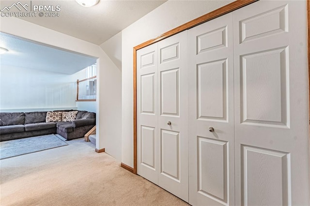 hall with lofted ceiling and light carpet