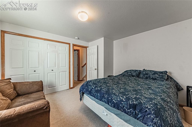 carpeted bedroom with a closet and a textured ceiling