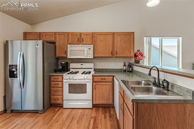 kitchen featuring white appliances, lofted ceiling, sink, and light hardwood / wood-style flooring