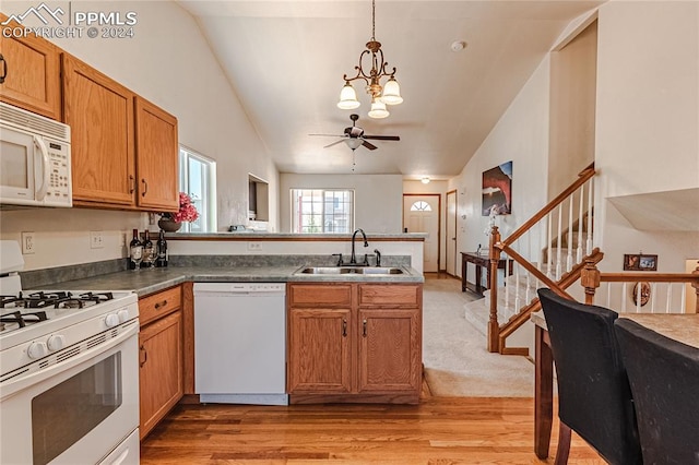 kitchen with white appliances, lofted ceiling, sink, and hanging light fixtures