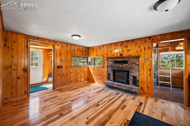 unfurnished living room featuring a brick fireplace, hardwood / wood-style floors, and wooden walls