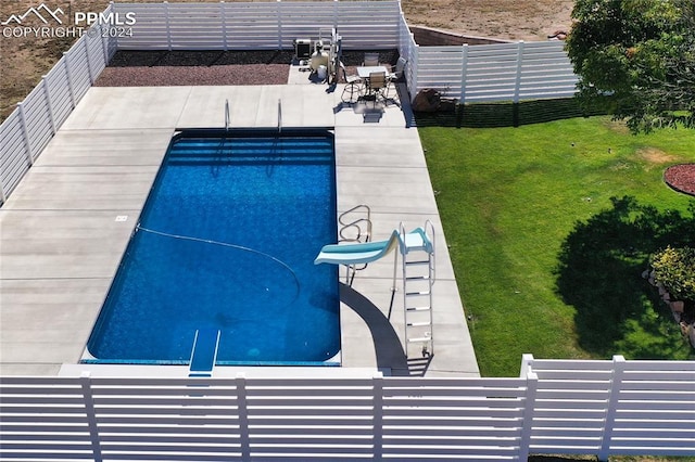 view of pool featuring a yard, a water slide, and a patio area