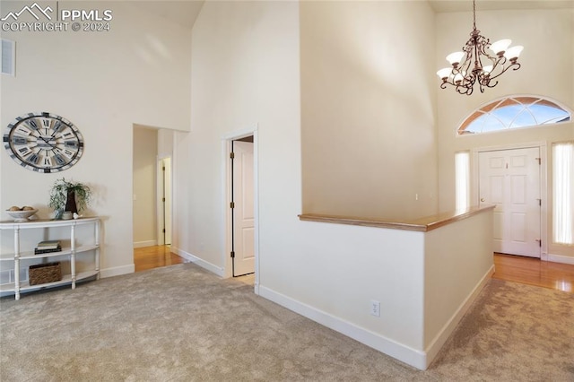 carpeted foyer entrance with a notable chandelier, plenty of natural light, and high vaulted ceiling