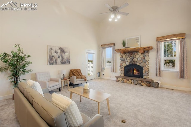 carpeted living room featuring high vaulted ceiling, ceiling fan, plenty of natural light, and a stone fireplace