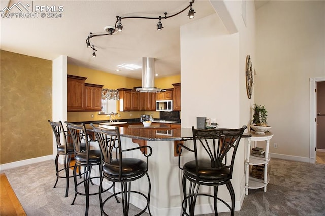 kitchen with a breakfast bar, sink, kitchen peninsula, island exhaust hood, and light hardwood / wood-style flooring