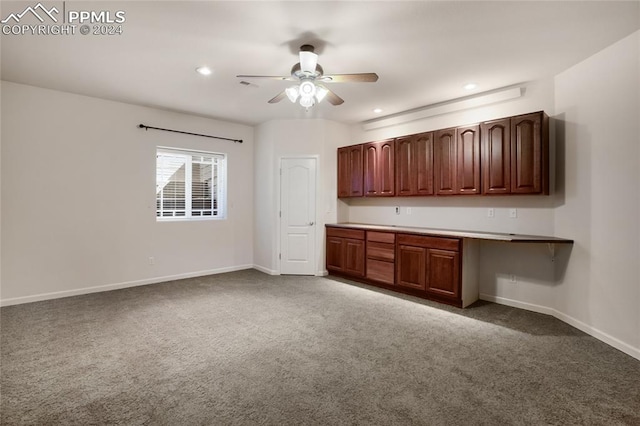 kitchen with built in desk, dark colored carpet, and ceiling fan