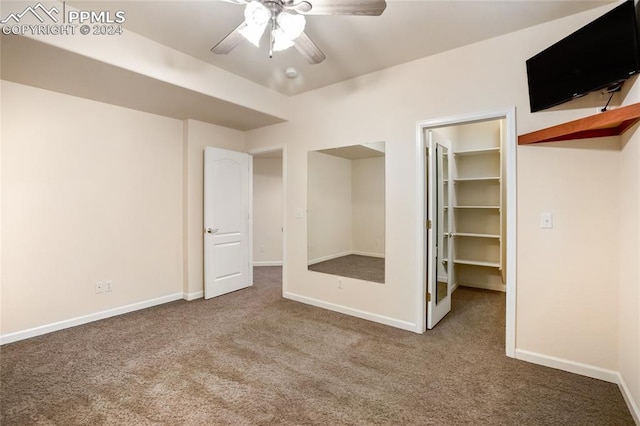 unfurnished bedroom with carpet flooring, ceiling fan, a walk in closet, and a closet