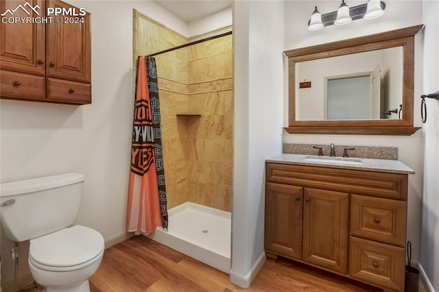 bathroom with walk in shower, vanity, toilet, and wood-type flooring