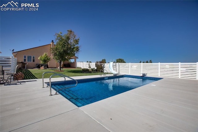 view of pool with a patio, a diving board, a lawn, and a water slide