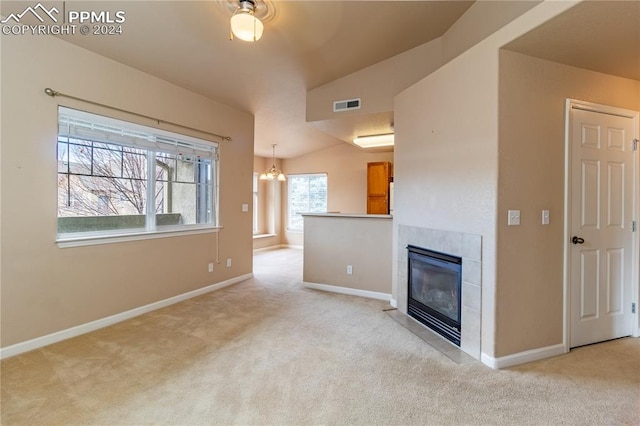 unfurnished living room with lofted ceiling, a fireplace, a chandelier, and a healthy amount of sunlight