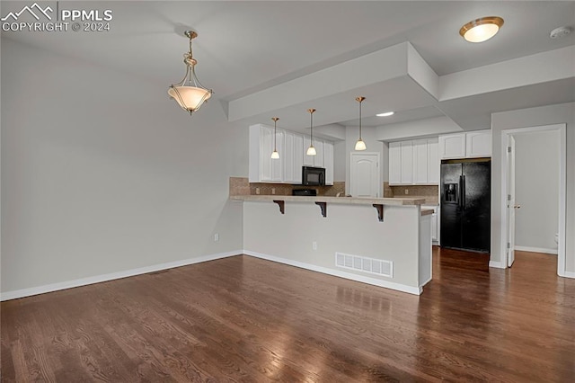 kitchen with white cabinetry, a kitchen bar, black appliances, dark hardwood / wood-style flooring, and kitchen peninsula