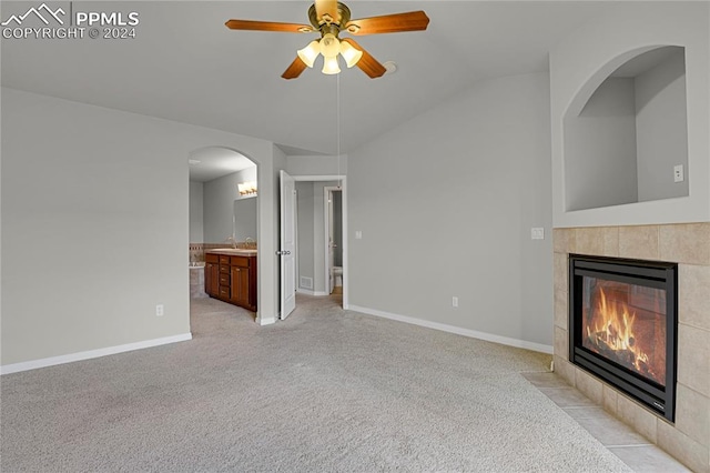 unfurnished living room featuring a fireplace, vaulted ceiling, light carpet, and ceiling fan