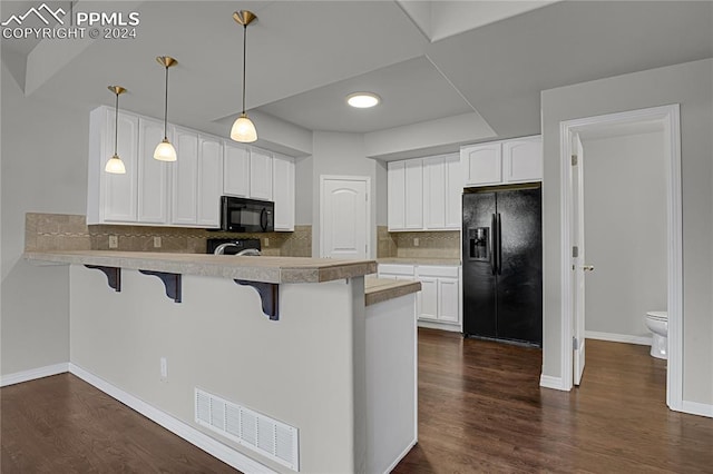 kitchen featuring black appliances, kitchen peninsula, dark hardwood / wood-style floors, and hanging light fixtures