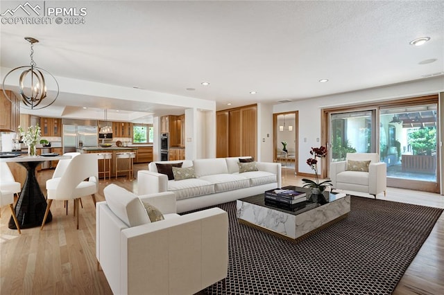 living room featuring a notable chandelier, light hardwood / wood-style flooring, and plenty of natural light