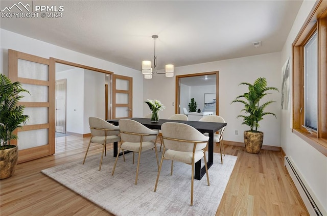 dining area featuring a baseboard radiator, a chandelier, and light hardwood / wood-style flooring